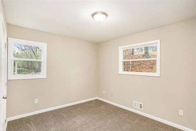 unfurnished room with visible vents, plenty of natural light, baseboards, and carpet flooring