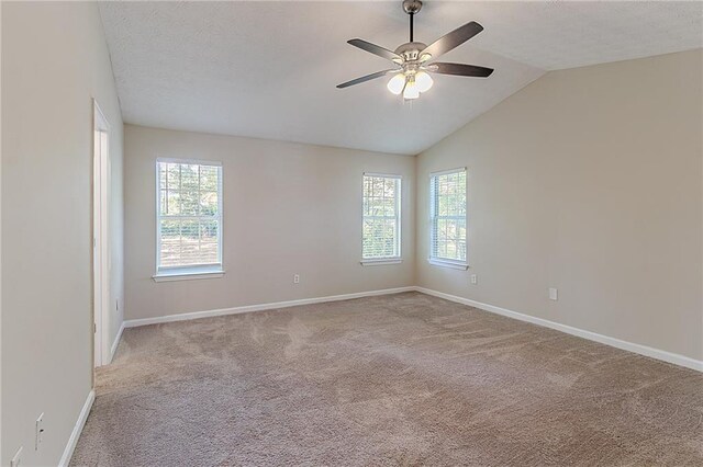 carpeted spare room with ceiling fan, baseboards, and vaulted ceiling