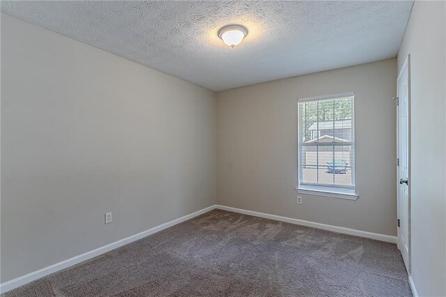 carpeted empty room featuring baseboards and a textured ceiling