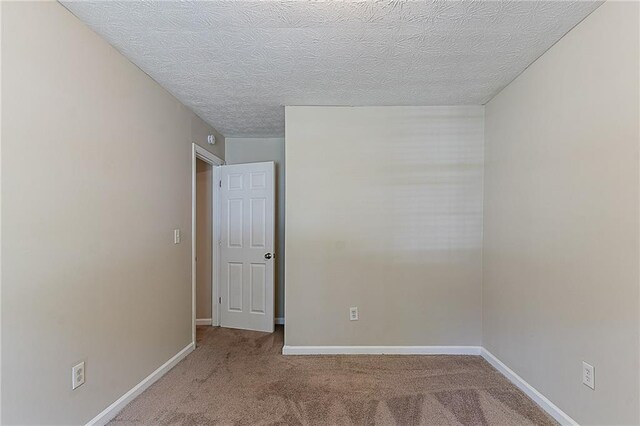 carpeted empty room with a textured ceiling and baseboards