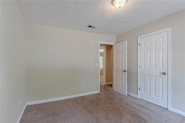unfurnished bedroom featuring carpet floors, baseboards, and a textured ceiling
