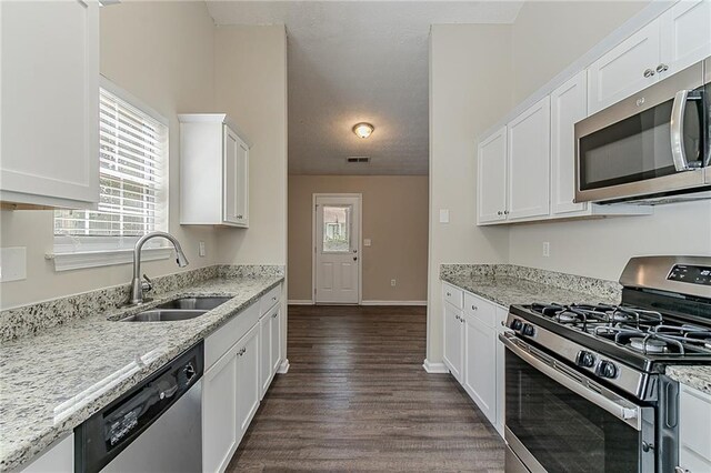 kitchen with stainless steel appliances, a sink, healthy amount of natural light, and white cabinetry