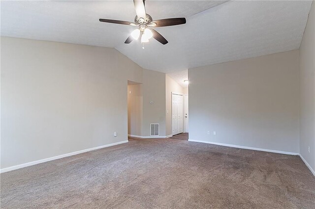 carpeted empty room featuring a ceiling fan, vaulted ceiling, and baseboards