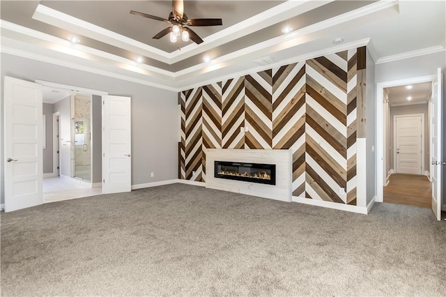 unfurnished living room with a raised ceiling, ceiling fan, light colored carpet, and crown molding