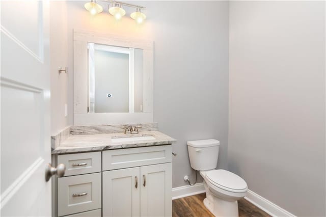 bathroom with hardwood / wood-style floors, vanity, and toilet