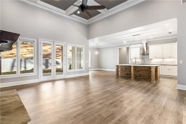 unfurnished living room with beam ceiling, a high ceiling, coffered ceiling, and ornamental molding