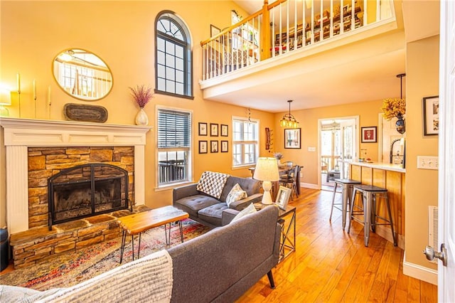 living room with baseboards, a high ceiling, hardwood / wood-style floors, and a fireplace