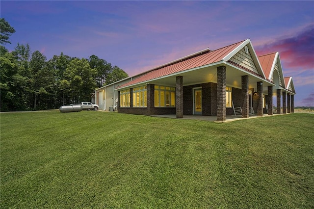 231 Gordon Rd, Cedartown, GA 30125 - back of house at dusk with a yard, a metal roof, brick siding, and a patio