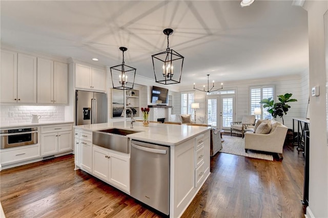 kitchen with open floor plan, stainless steel appliances, dark wood-type flooring, and a sink