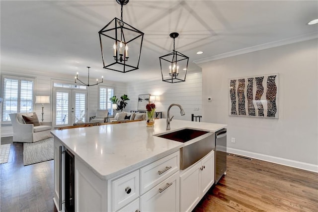 kitchen featuring a kitchen island with sink, pendant lighting, open floor plan, and wood finished floors