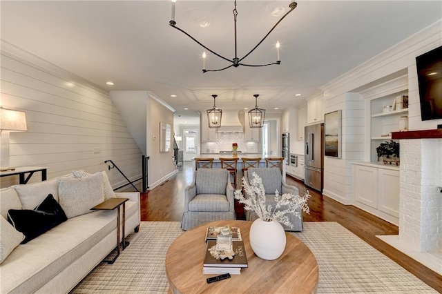 living room featuring dark wood-style floors, a fireplace, crown molding, recessed lighting, and a chandelier