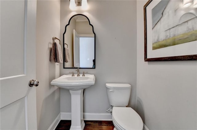 half bath featuring toilet, baseboards, and wood finished floors