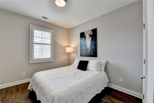 bedroom with wood finished floors, visible vents, and baseboards