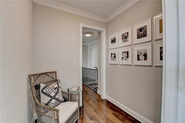 corridor with ornamental molding, an upstairs landing, baseboards, and wood finished floors