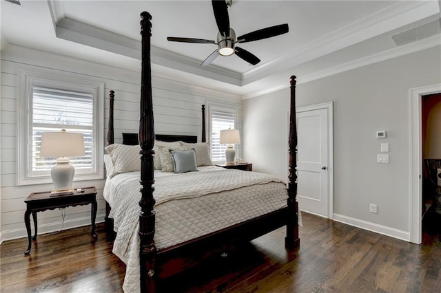 bedroom featuring crown molding, visible vents, a raised ceiling, and wood finished floors