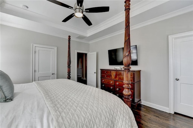 bedroom featuring baseboards, a ceiling fan, wood finished floors, a tray ceiling, and crown molding