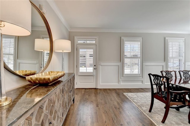 entryway with wainscoting, a healthy amount of sunlight, crown molding, and wood finished floors