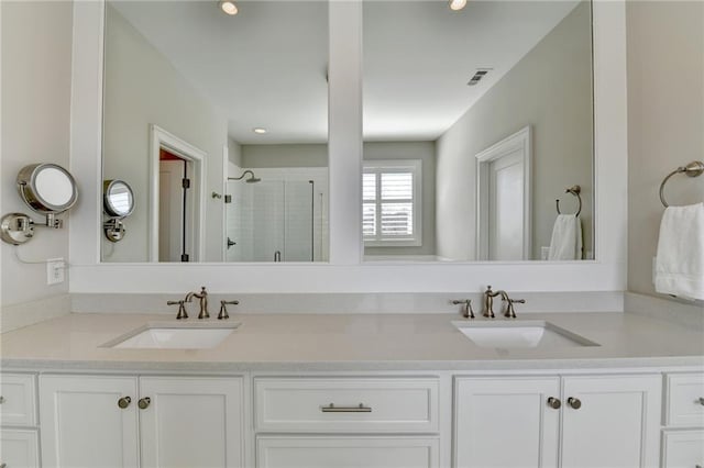 full bath featuring a sink, double vanity, a shower stall, and visible vents