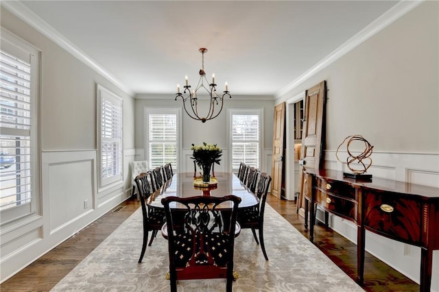 dining room with a chandelier, a decorative wall, a wainscoted wall, ornamental molding, and dark wood-style floors