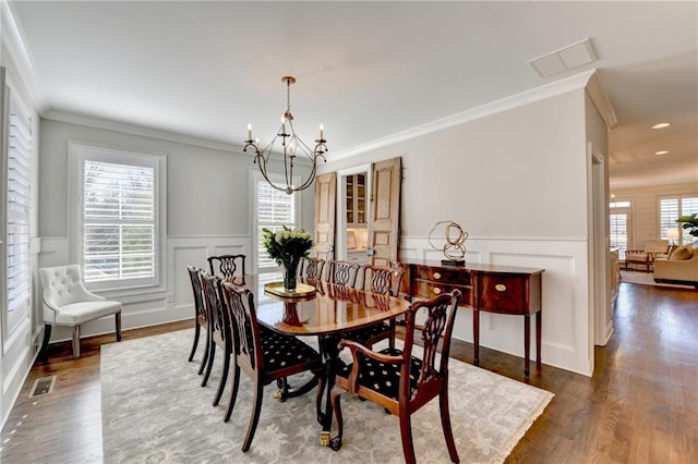 dining area featuring an inviting chandelier, visible vents, dark wood-style flooring, and ornamental molding