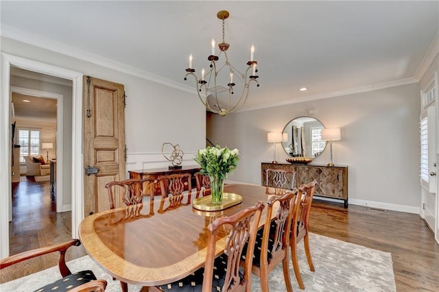 dining area with a notable chandelier, crown molding, baseboards, and wood finished floors