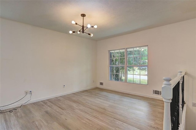 6454 Boca Grande Blvd, Forest Park, GA 30297 - spare room with a chandelier, light wood-style flooring, baseboards, and a textured ceiling