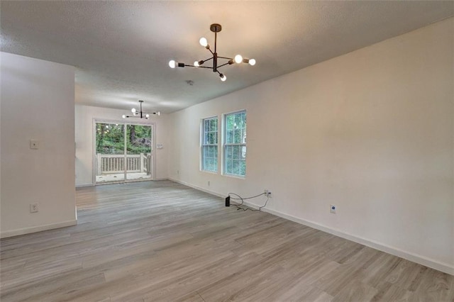 6454 Boca Grande Blvd, Forest Park, GA 30297 - empty room with a chandelier, light wood finished floors, baseboards, and a textured ceiling
