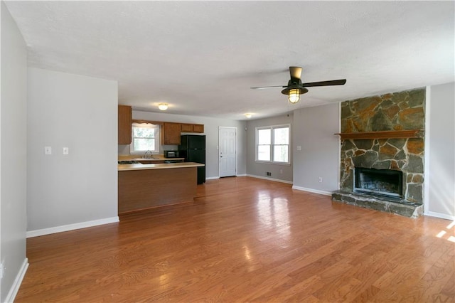 37 Indian Hills Ct, Dallas, GA 30157 - unfurnished living room featuring a fireplace, a ceiling fan, a sink, light wood-type flooring, and baseboards