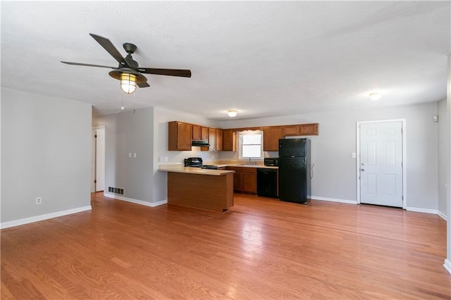 37 Indian Hills Ct, Dallas, GA 30157 - kitchen with light wood-style flooring, under cabinet range hood, light countertops, black appliances, and brown cabinetry