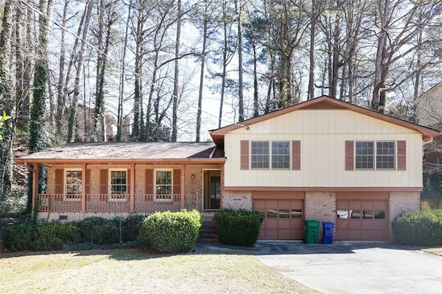 tri-level home featuring covered porch, a front yard, and a garage