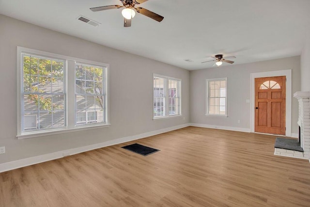 unfurnished living room featuring a fireplace, ceiling fan, and light hardwood / wood-style flooring