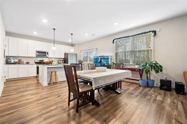 dining space with light wood-style flooring, recessed lighting, and baseboards