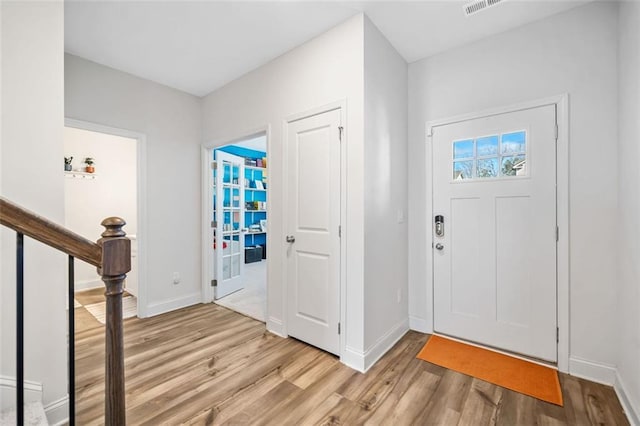 foyer entrance featuring stairway, light wood-style flooring, and baseboards