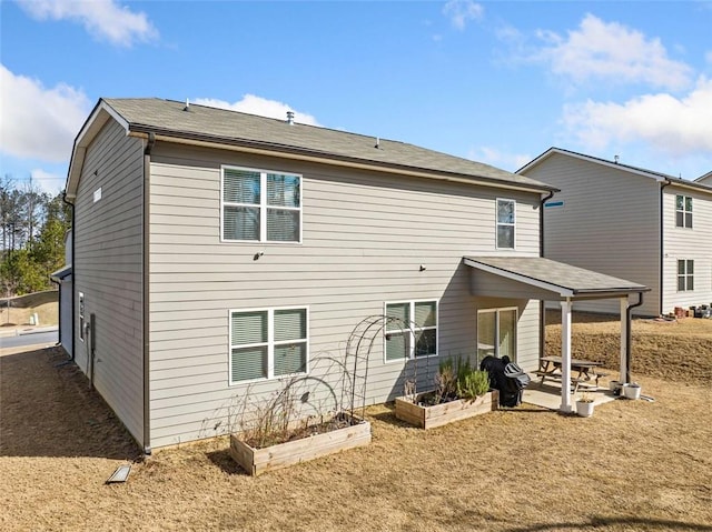 rear view of property featuring a garden and a patio area