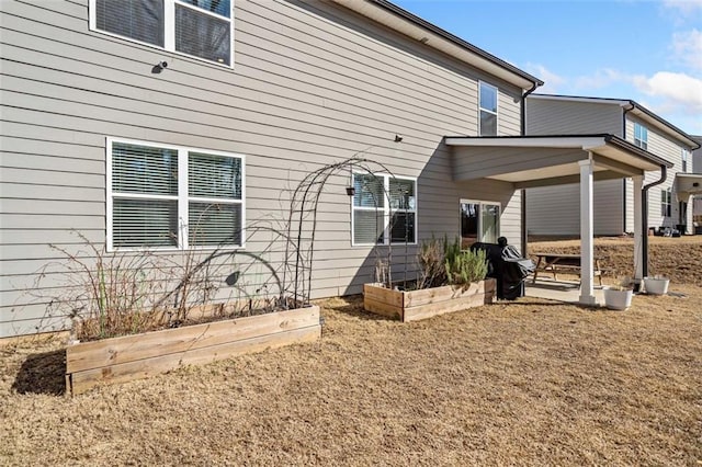 rear view of property featuring a garden and a patio area