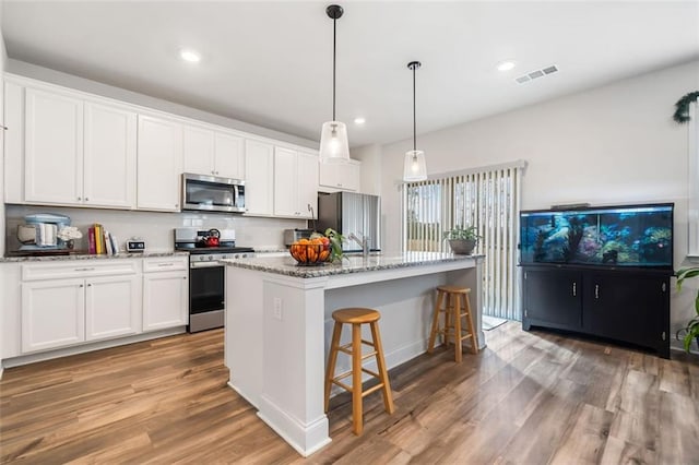 kitchen with visible vents, a center island with sink, white cabinets, and stainless steel appliances