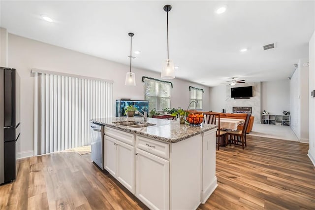 kitchen with wood finished floors, visible vents, freestanding refrigerator, a sink, and stainless steel dishwasher