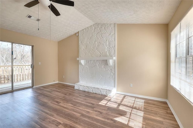 unfurnished living room with a wealth of natural light, visible vents, a fireplace, and wood finished floors