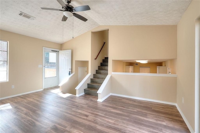 interior space featuring visible vents, wood finished floors, stairs, vaulted ceiling, and a textured ceiling