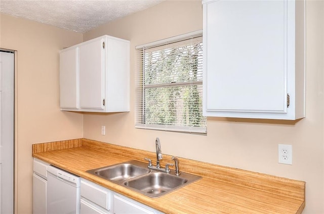 kitchen featuring light countertops, white cabinets, white dishwasher, and a sink