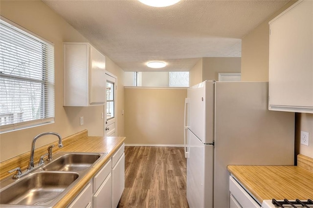 kitchen featuring light countertops, white cabinetry, a sink, and wood finished floors