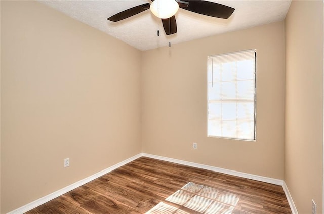 unfurnished room featuring dark wood-style floors, ceiling fan, baseboards, and a textured ceiling