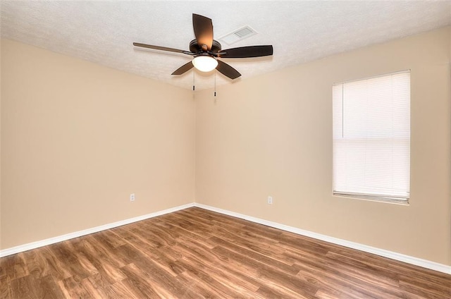 unfurnished room with a textured ceiling, wood finished floors, and baseboards