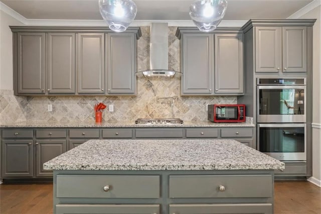 kitchen with appliances with stainless steel finishes, gray cabinets, and wall chimney exhaust hood