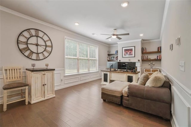 living area featuring wainscoting, a ceiling fan, ornamental molding, and dark wood-style flooring