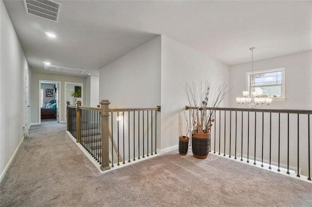 corridor with carpet floors, baseboards, a chandelier, and visible vents