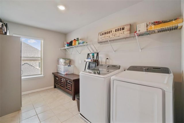 laundry area featuring light tile patterned flooring, laundry area, washing machine and dryer, and baseboards