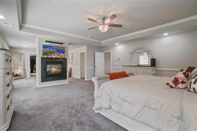 carpeted bedroom featuring visible vents, a raised ceiling, ceiling fan, and a multi sided fireplace