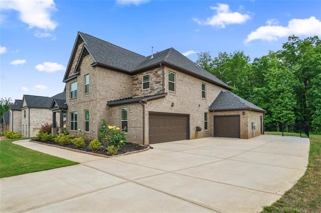 view of home's exterior with brick siding, fence, concrete driveway, an attached garage, and a shingled roof