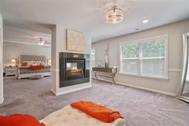 interior space featuring carpet floors, visible vents, baseboards, ceiling fan, and a multi sided fireplace